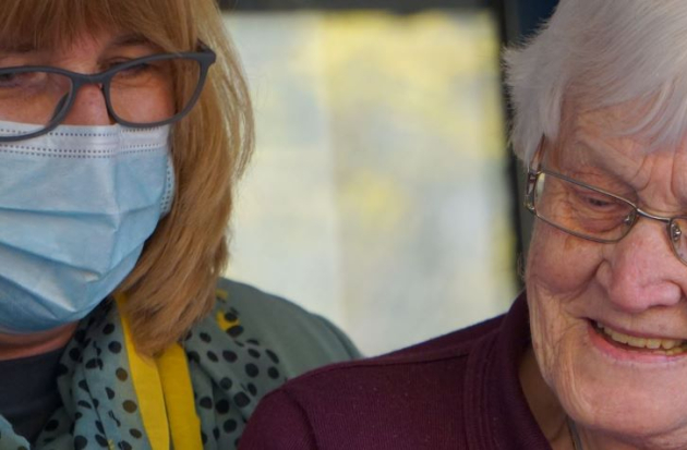 Oudere en jongere met mondkapje mobiel kijken