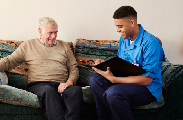 Zorgmedewerker op bank bij oudere man