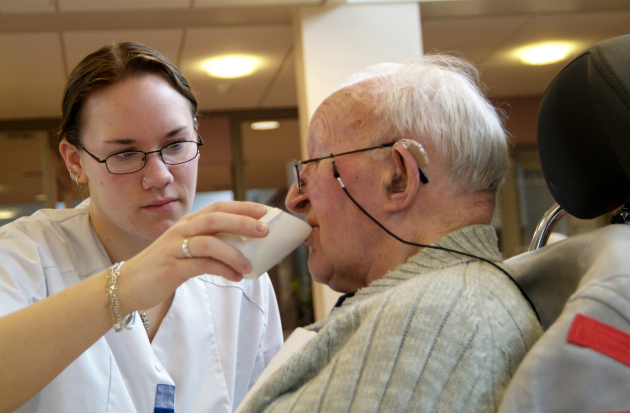 verzorgende helpt man bij drinken 