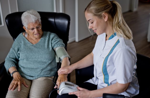 Wijkverpleging meet bloeddruk bij dame 