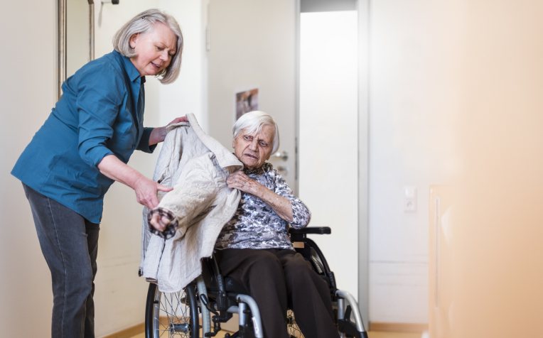 Oprechte aandacht - mantelzorger met vrouw in rolstoel 