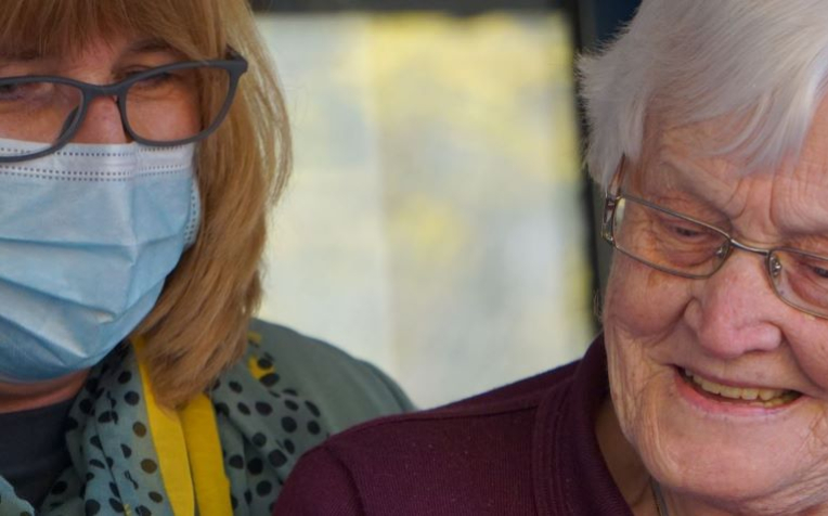 Oudere en jongere met mondkapje mobiel kijken