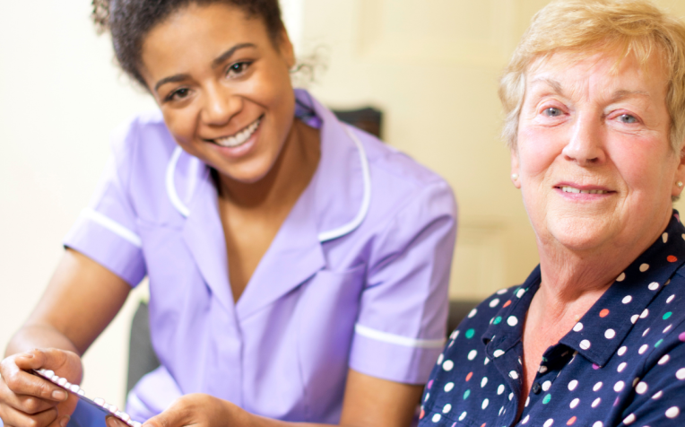 Verpleegkundige geeft pillen aan oudere