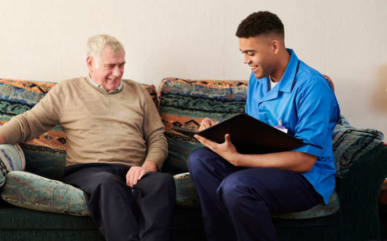 Zorgmedewerker op bank bij oudere man
