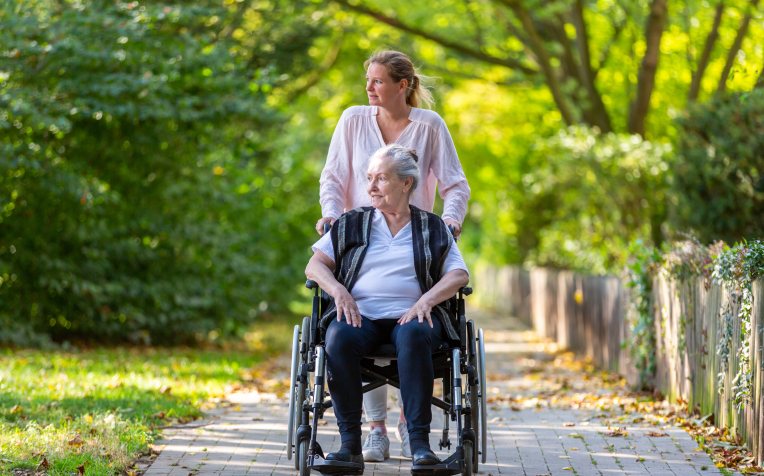 dame in rolstoel met mantelzorger