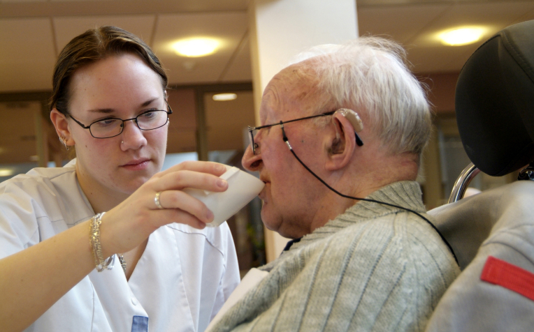 verzorgende helpt man bij drinken 