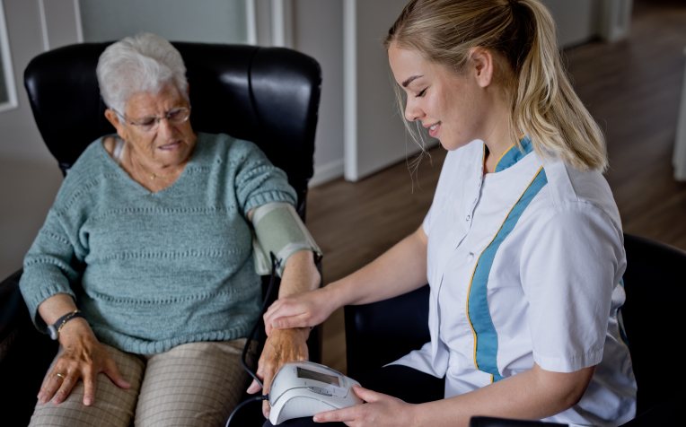 Wijkverpleging meet bloeddruk bij dame 