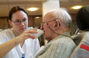 verzorgende helpt man bij drinken 