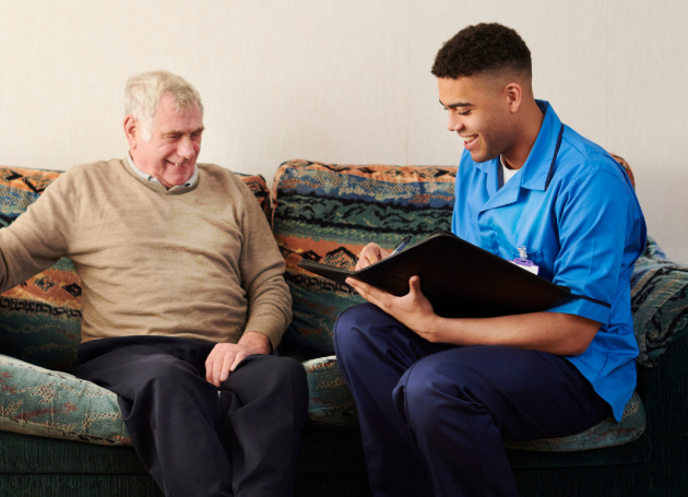 Zorgmedewerker op bank bij oudere man