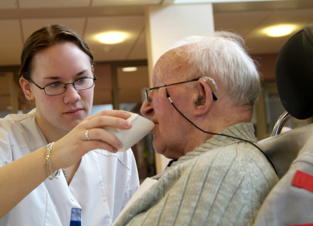 verzorgende helpt man bij drinken 