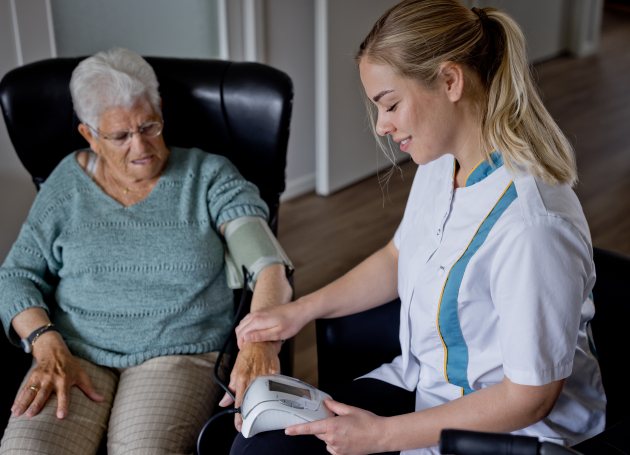 Wijkverpleging meet bloeddruk bij dame 