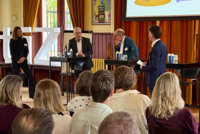 Foto van panelleden in gesprek tijdens het live event De hub naar huis
